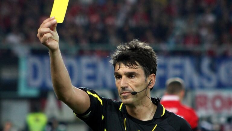 A football referee holding up a yellow card during a match