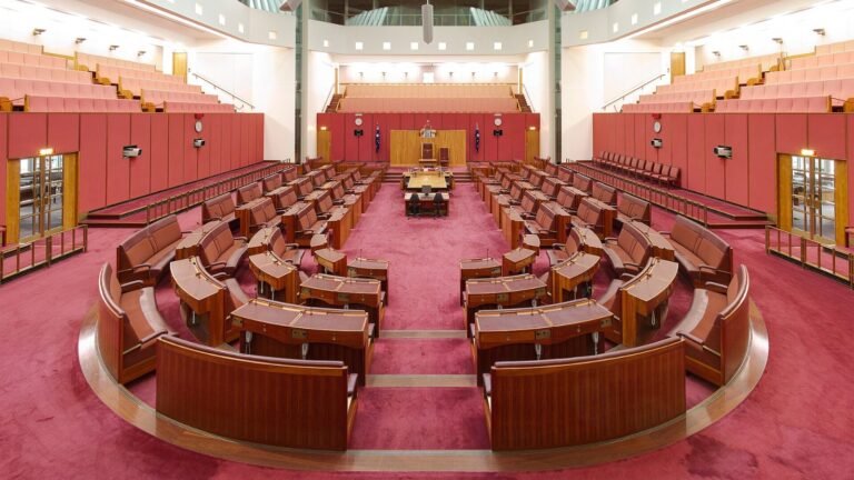 An empty parliamentary debating chamber with rows of benches